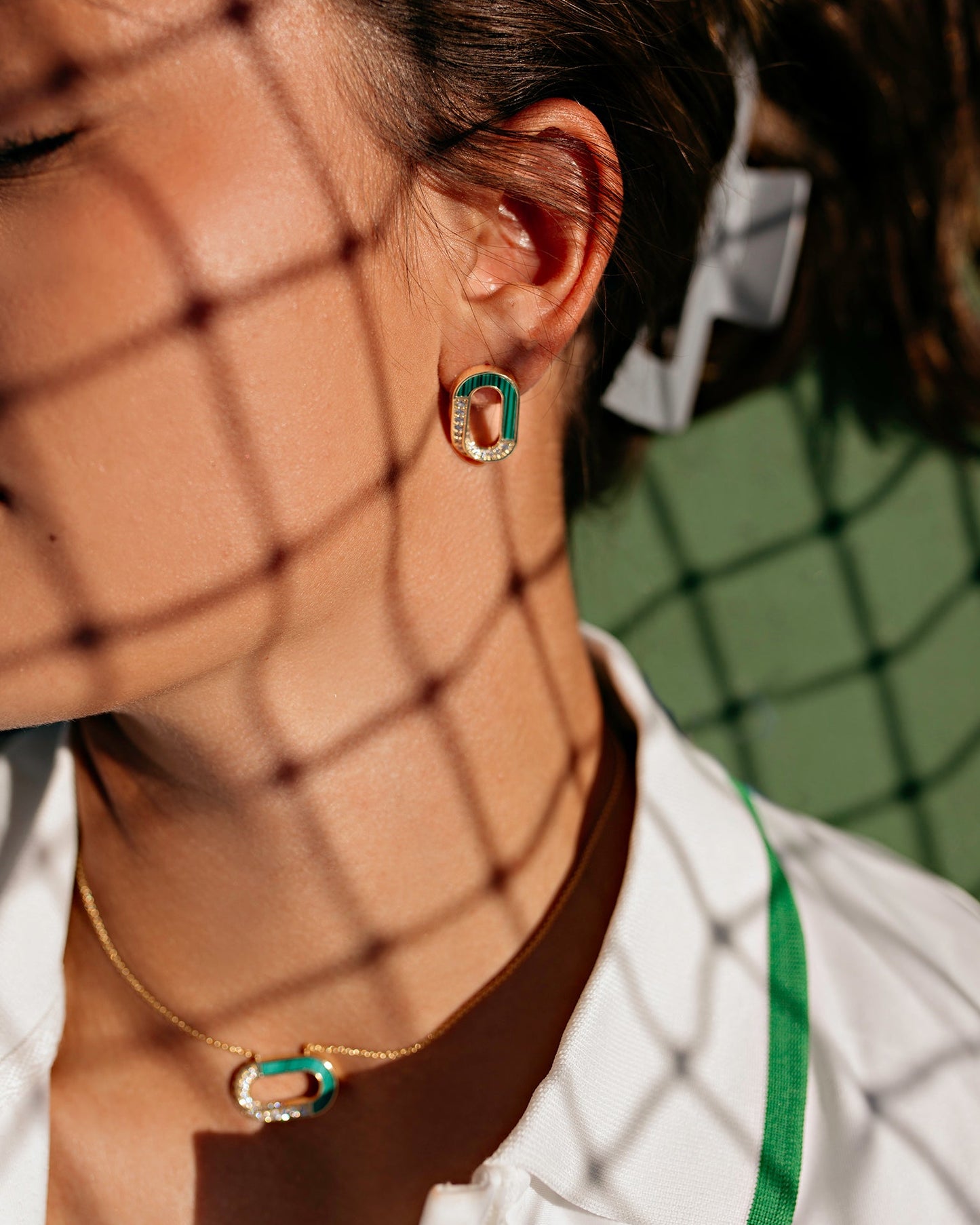 Person wearing a white jacket with green accents, standing behind a wire mesh.