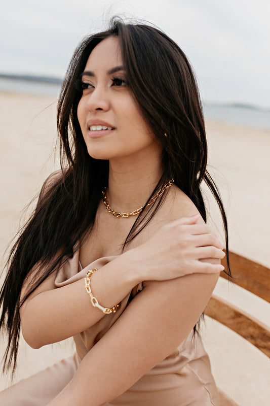 Gold necklace and bracelet set for the beach on a girl with a gold dress and dark hair