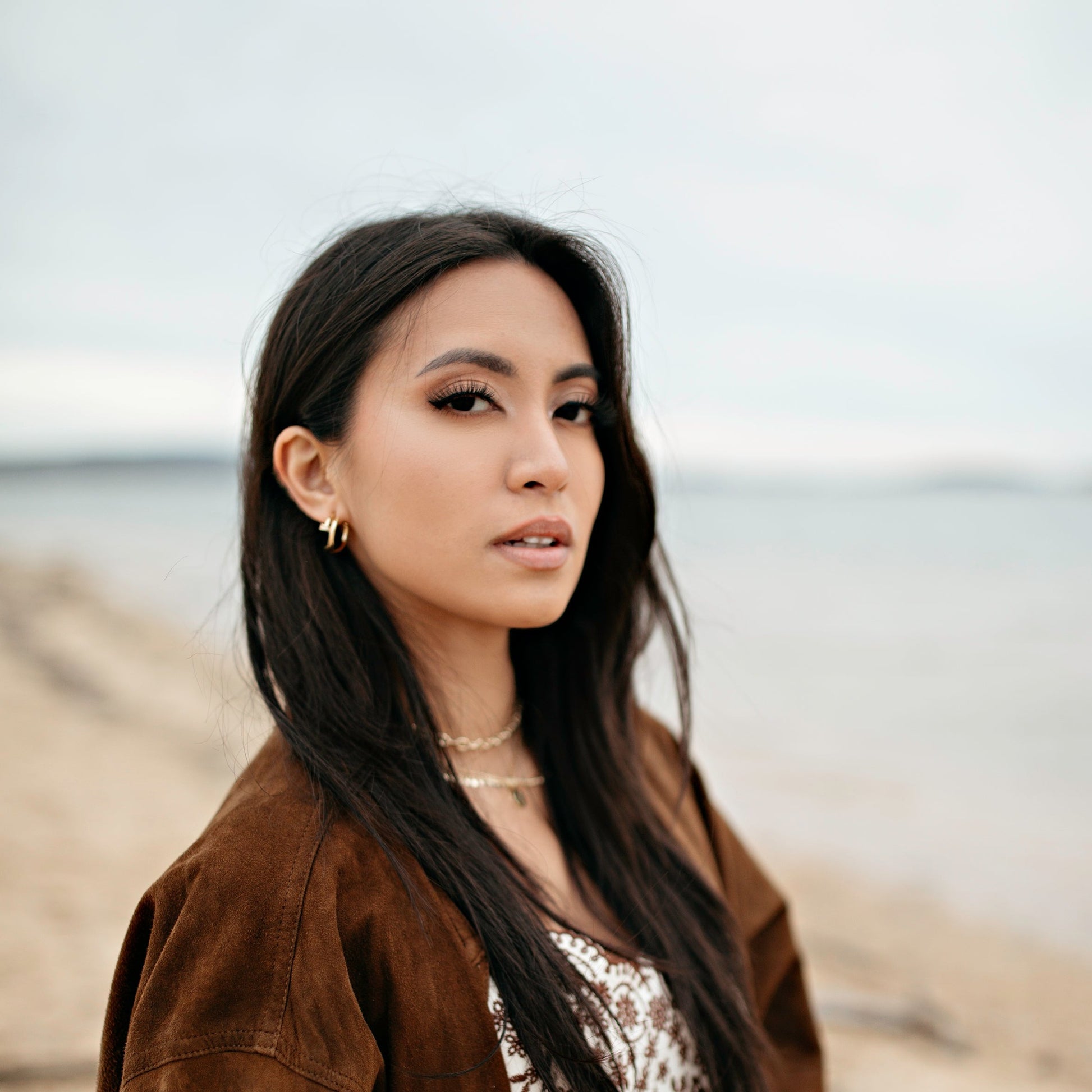 woman wearing gold jewlery at the beach