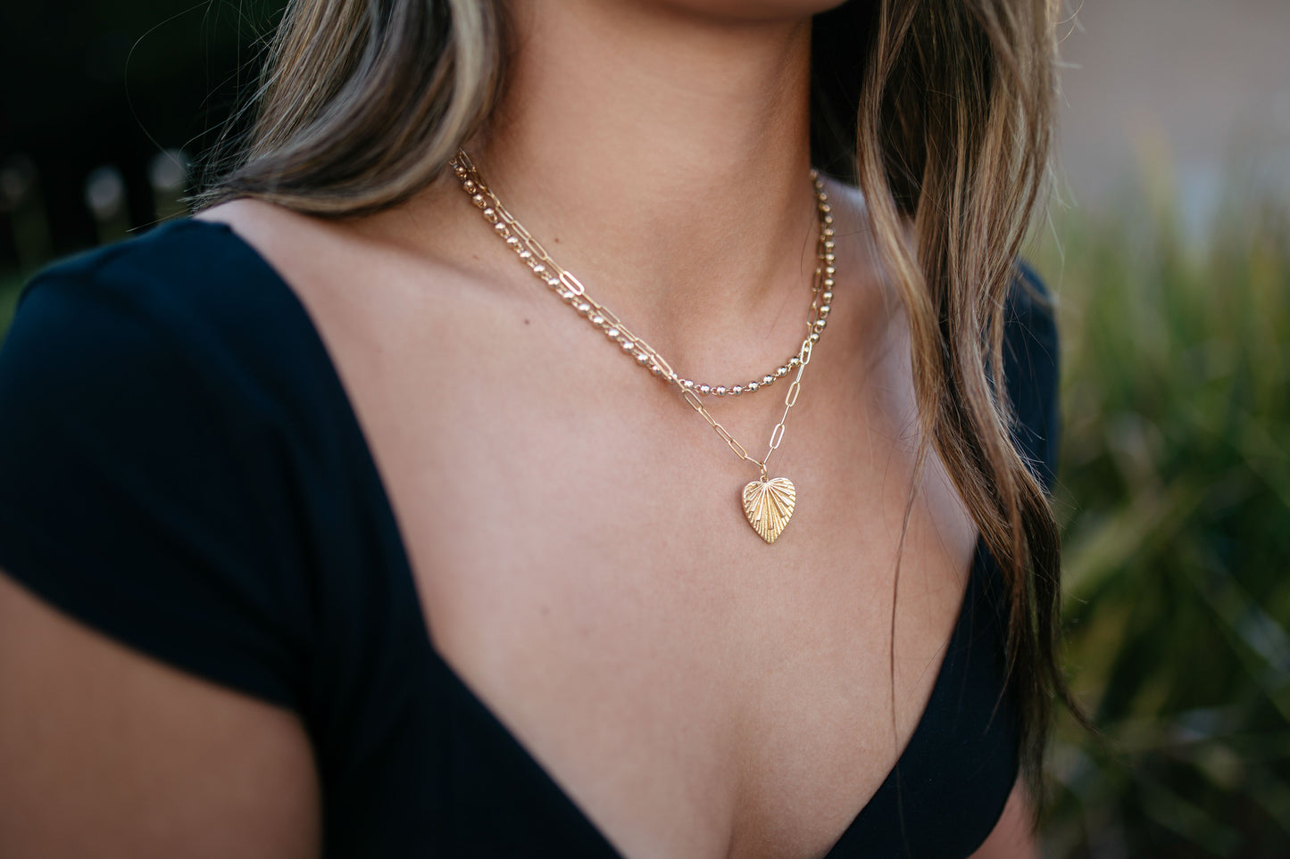 Gold leaf charm on paperclip chain necklace with other gold bella chain on girl with black shirt 