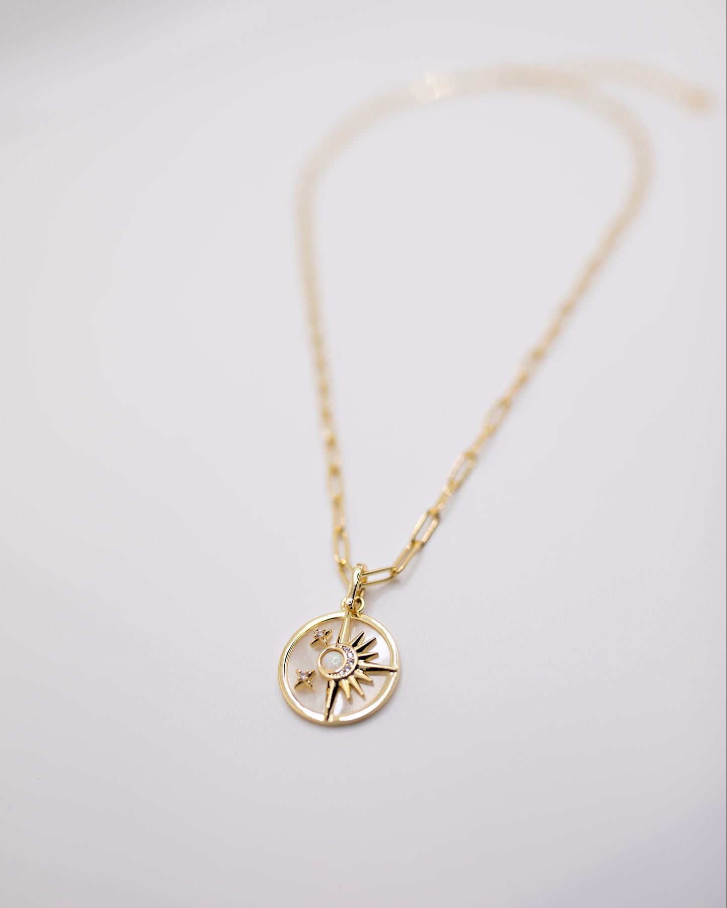 Gold Celestial necklace with a circular pendant on a light gray background