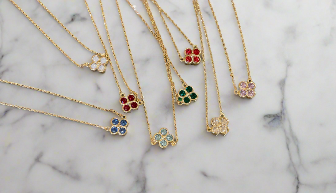 Gold necklaces with floral pendants on a marble surface