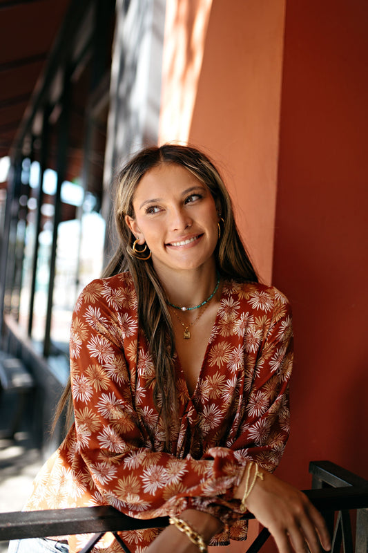 Girl wearing gold and turquoise necklaces with buterfly and pearl charms for fall outfits. 