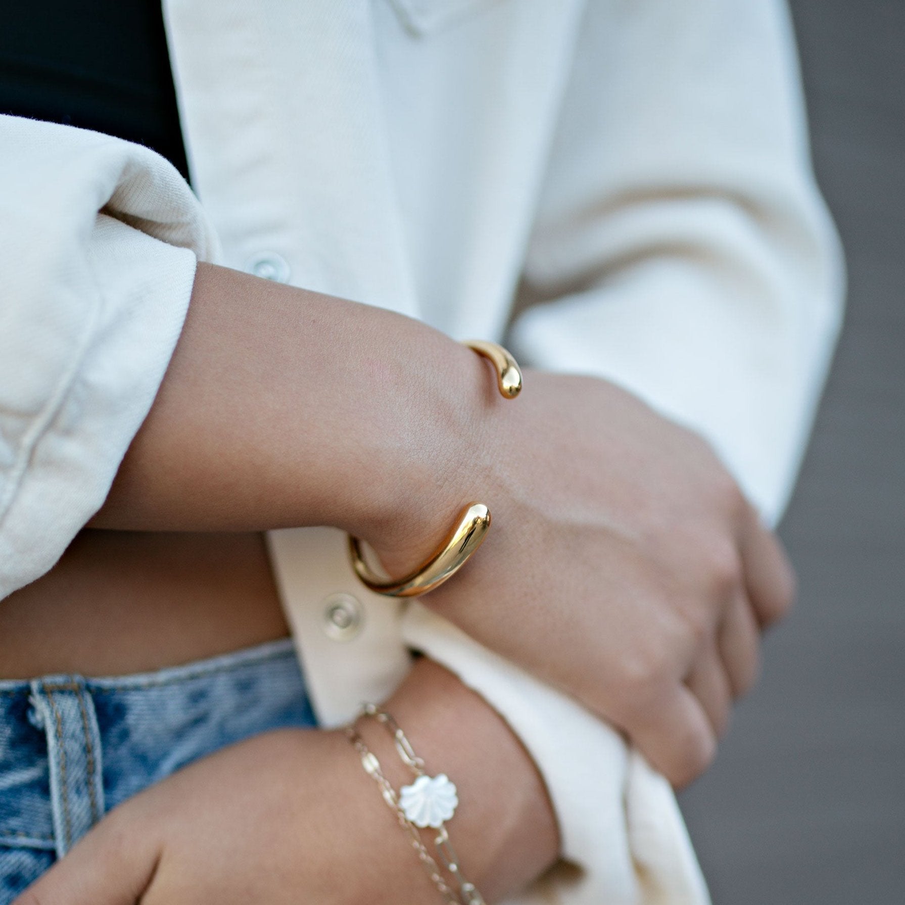 Gold bracelet with white top and blue jeans